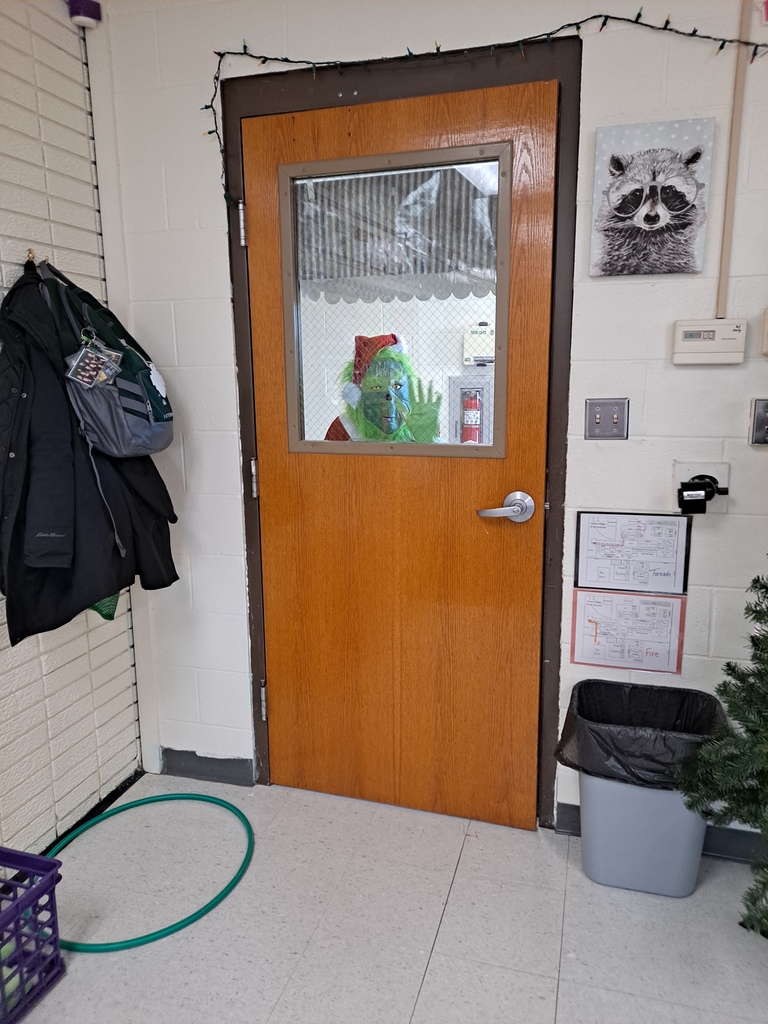 The Grinch looking through a classroom door window.